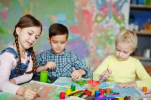 Three children doing craft activities together at a table