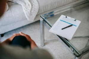 From above of blurred unrecognizable female psychologist sitting in office near table with clipboard and pen during session in office