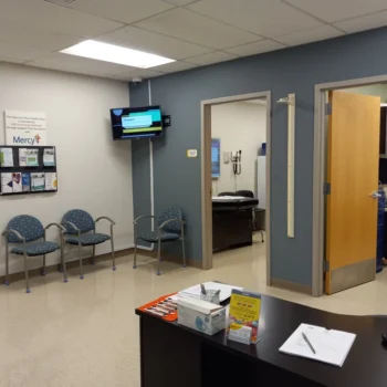 Therapy clinic waiting room with blue chairs, a reception desk and an open consultation room