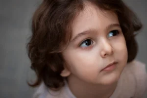Charming close-up portrait of a young child with big, expressive eyes and curly hair