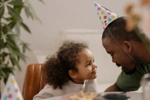Father and daughter share a joyful moment at a birthday celebration at home
