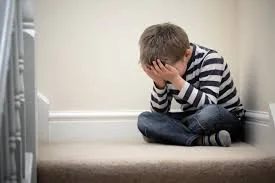 A boy sitting on stairs with his head in his hands