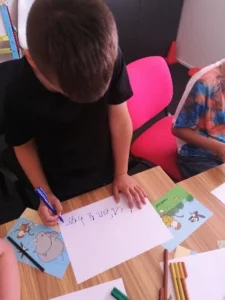 Children drawing and writing at a table during an occupational therapy session