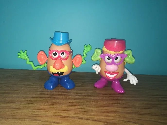 Two Mr Potato Head toys standing on a wooden floor