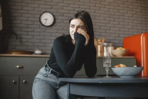 Young woman in a pensive mood, sitting indoors with a clock in the background