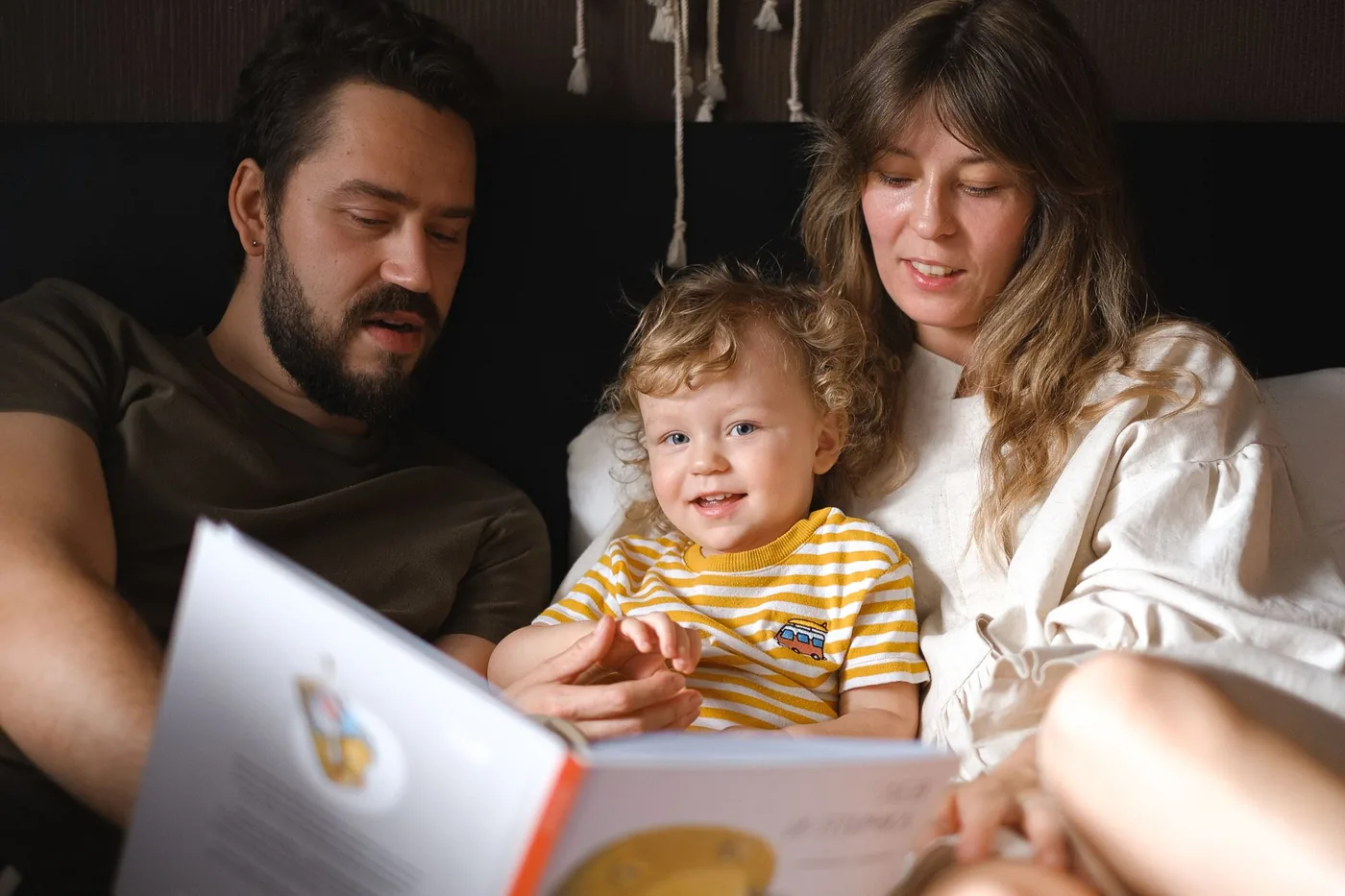 A happy family reading together, featuring parents and their smiling child enjoying a book indoors