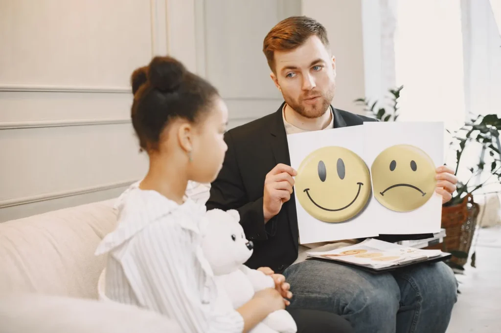 A therapist uses emotion cards to help a child express feelings during a counseling session