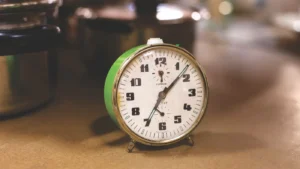 Close-up of a retro alarm clock next to kitchen pots, emphasizing time management in cooking