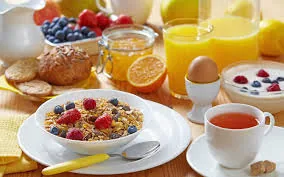 A breakfast spread of cereal, fruit, pastries, juice and a boiled egg