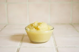 Close-up of homemade applesauce in a clear glass bowl on a tiled surface