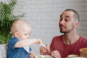 Father and baby enjoying a playful mealtime together at home