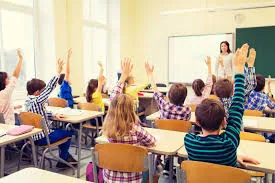 School children raising their hands in a classroom