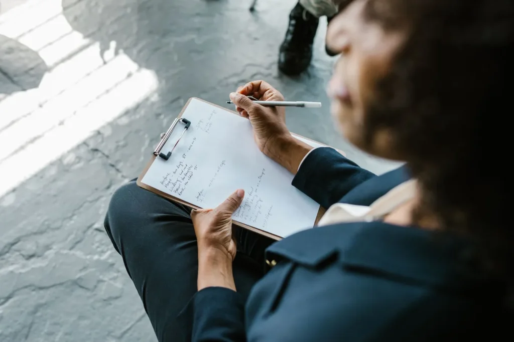 Close-up of a therapist writing notes on clipboard during a counseling session