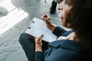 Close-up of a therapist writing notes on clipboard during a counseling session