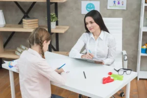 Smiling female psychologist observing girl during therapy session