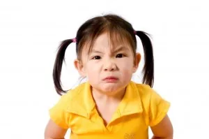 A young girl in a yellow polo shirt with an unimpressed expression